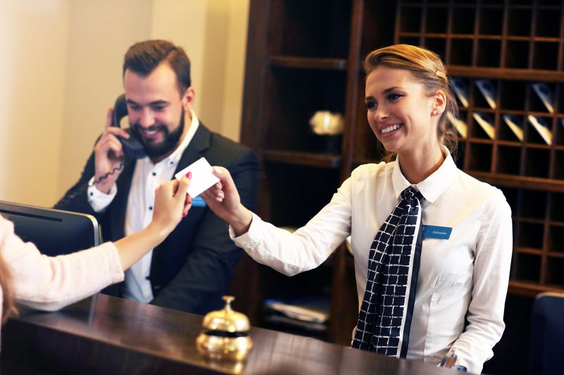 Frau an Rezeption übergibt Schlüsselkarte für Hotelzimmer
